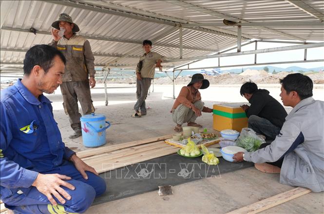 Một nhóm công nhân ăn, nghỉ khẩn trương ngay trên công trường. Ảnh: Nguyễn Dũng – TTXVN 
