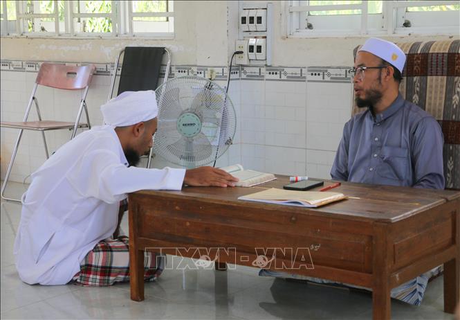 Học sinh người dân tộc Chăm ở cấp độ số 4 (đọc thuộc, đúng âm điệu Kinh Al-Qur’an và giáo lý Islam nâng cao) đang trả bài tập với thầy giáo sau mỗi tuần học. Ảnh: Công Mạo - TTXVN