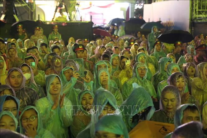 Người dân cùng các chiến sĩ Công an nhân dân đội mưa xem chương trình Gala “Tổ quốc bình yên”. Ảnh: Hồng Đạt - TTXVN