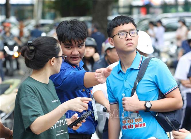 Các tình nguyện viên hướng dẫn phụ huynh và thí sinh vào khu vực thi. Ảnh: Bùi Tiến Long - TTXVN phát