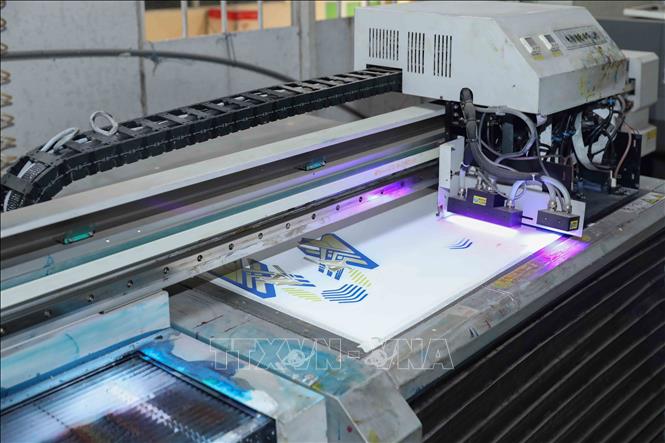 Máy in UV tại Công ty TNHH Nam Bình được sử dụng để in tự động và phát triển mẫu, là một trong những công nghệ hiện đại nhất Việt Nam. Hệ thống này được ứng dụng trực tiếp vào dây chuyền may giày nhằm nâng cao chất lượng và năng suất. Ảnh: Phan Phương – TTXVN
