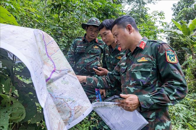Các thành viên Đội tìm kiếm xác minh thông tin được thân nhân liệt sĩ cung cấp với bản đồ trên thực địa. Ảnh: Hoàng Hiếu - TTXVN