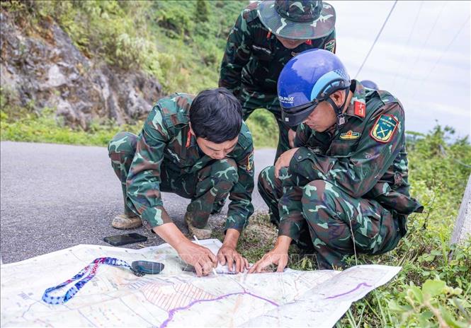 Trung tá Hoàng Vũ Dũng - Đội phó Đội tìm kiếm, quy tập hài cốt liệt sĩ Tuyên Quang cùng các thành viên trong Đội tổ chức đo đạc, đối chiếu thông tin được cung cấp với bản đồ thực tế. Ảnh: Hoàng Hiếu - TTXVN
