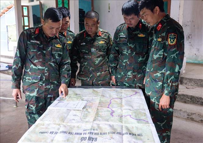 So sánh, đối chiếu bản đồ với sơ đồ mộ phần liệt sĩ hy sinh tại xã Minh Tân được thân nhân liệt sĩ cung cấp. Ảnh: Hoàng Hiếu - TTXVN
