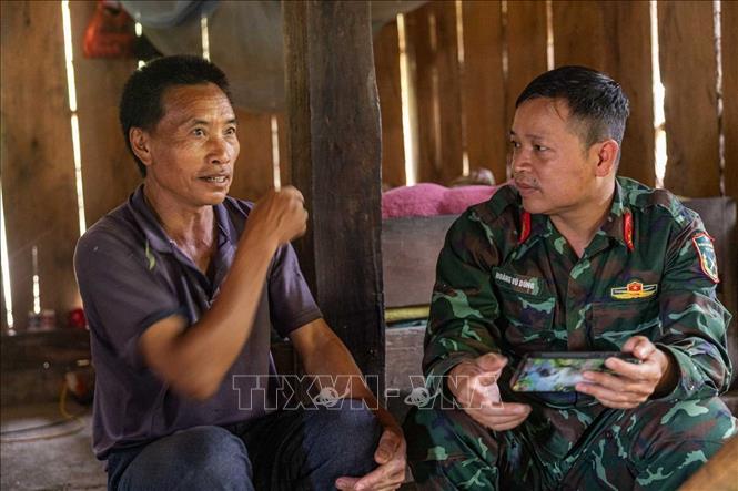 Trung tá Hoàng Vũ Dũng trao đổi, xác minh thông tin được cung cấp với ông Vàng Xeo Phù - Chủ tịch MTTQ Thôn Hoàng Đình Phả - người sống gần địa điểm nghi mộ phần 12 liệt sĩ. Ảnh: Hoàng Hiếu - TTXVN