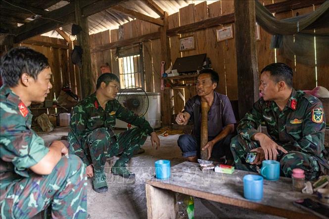 Trung tá Hoàng Vũ Dũng trao đổi, xác minh thông tin với ông Vàng Xeo Phù - Chủ tịch Mặt trận Tổ quốc thôn Hoàng Đình Phả - người sống gần địa điểm nghi mộ phần 12 liệt sĩ. Ảnh: Hoàng Hiếu - TTXVN