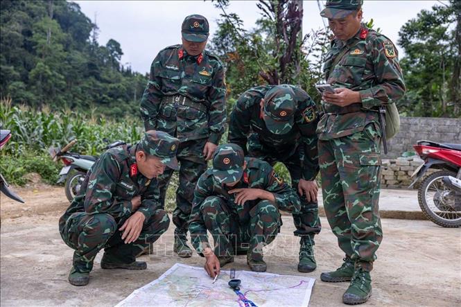 Các thành viên trong đội xác minh thông tin về sơ đồ vực mộ chí liệt sĩ (được thân nhân liệt sĩ cung cấp) tại hiện trường, mong sớm đưa “đồng đội” về với gia đình, quê hương. Ảnh: Hoàng Hiếu - TTXVN