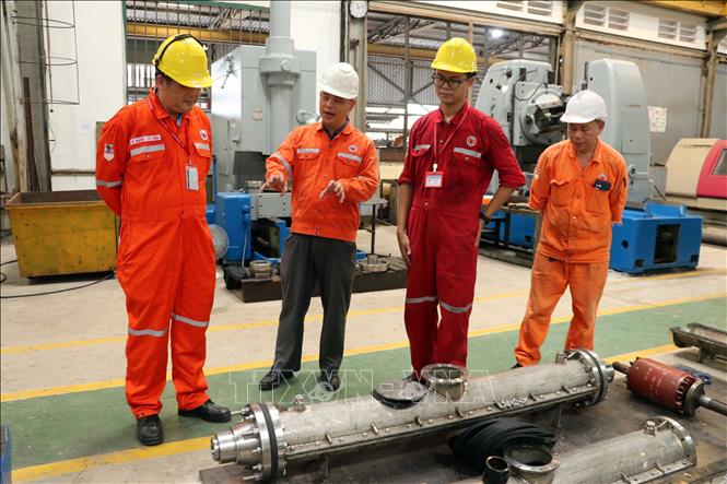 Đội ngũ kỹ sư Xí nghiệp Cơ điện kiểm tra hộp nối cáp ngầm vừa được chế tạo. Ảnh: Đoàn Mạnh Dương - TTXVN