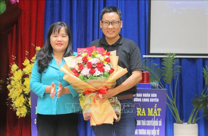 Bà Đoàn Thị Hương Hà, Chủ tịch UBND phường Long Xuyên (tỉnh An Giang) tặng hoa cho đại diện danh nghiệp trực tiếp hố trợ thực hiện xây dựng Hệ sinh thái chuyển đổi số và Cổng thương mại điện tử. Ảnh: Công Mạo -TTXVN