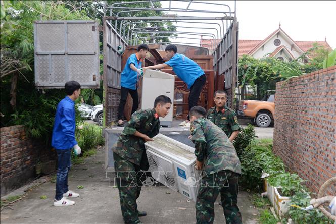 Lực lượng quân đội, thanh niên tình nguyện giúp người dân thôn Thủ Pháp, xã Gia Bình di chuyển đồ đạc đến nơi ở tạm. Ảnh: Việt Hùng - TTXVN

