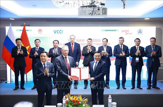 PM Le Minh Hung witnesses the exchange of cooperation documents between the two countries' businesses. VNA Photo: Dương Giang 
