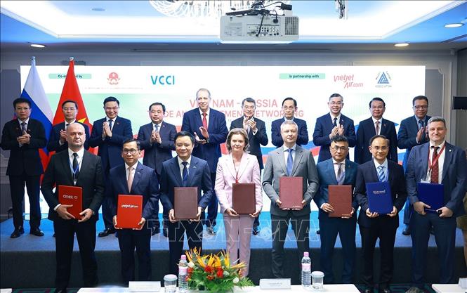 PM Le Minh Hung witnesses the exchange of cooperation documents between the two countries' businesses. VNA Photo: Dương Giang 