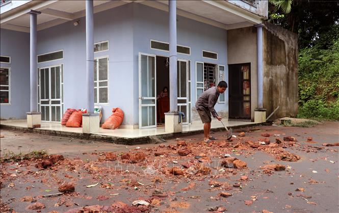 Người dân tranh thủ dọn dẹp đất đá, bùn đất để sớm khôi phục sinh hoạt. Ảnh: Đức Thọ - TTXVN