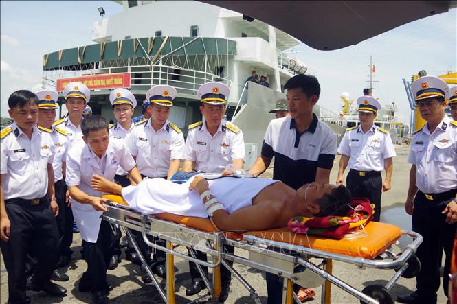 Đưa bệnh nhân Nguyễn Xuân Tùng lên xe cứu thương. Ảnh: TTXVN phát 