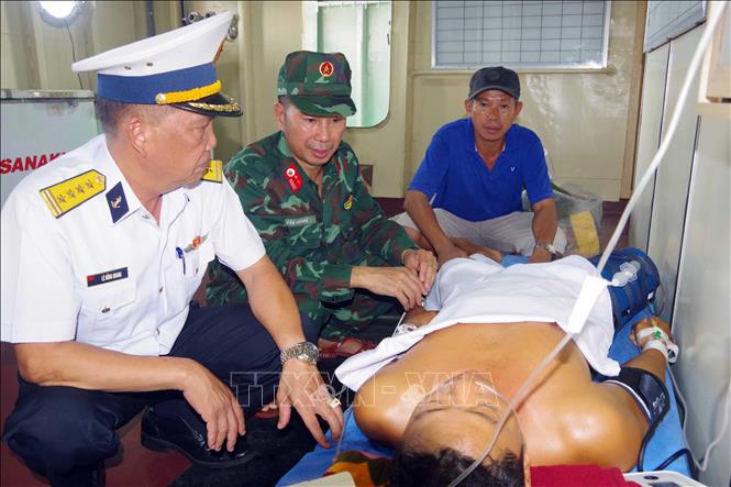 Đại tá Lê Hồng Quang, Phó Chủ nhiệm Chính trị Vùng 2 Hải quân thăm hỏi ngư dân Nguyễn Xuân Tùng. Ảnh: TTXVN phát 