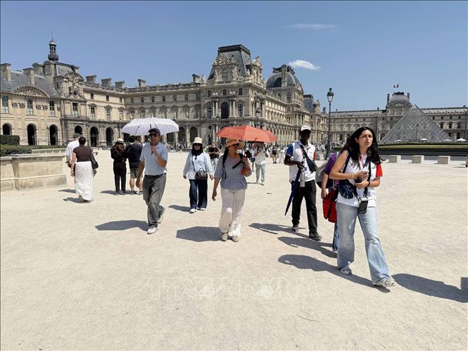 Nhiều du khách mang theo ô và nước uống khi tham quan bảo tàng Louvre trong đợt nắng nóng tại Paris. Ảnh: Hữu Chiến - PV TTXVN tại Pháp