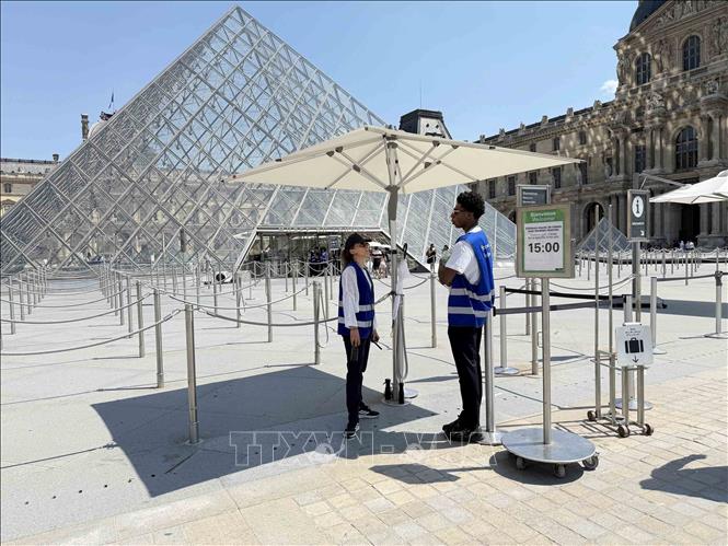 Nhân viên bảo tàng Louvre làm việc dưới mái che được bố trí tại khu vực đón khách trong thời tiết nắng nóng. Ảnh: Hữu Chiến - PV TTXVN tại Pháp