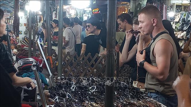 Khách quốc tế yêu thích việc mua sắm quà lưu niệm tại chợ đêm phố cổ Hà Nội. Ảnh: Tuyết Mai - TTXVN