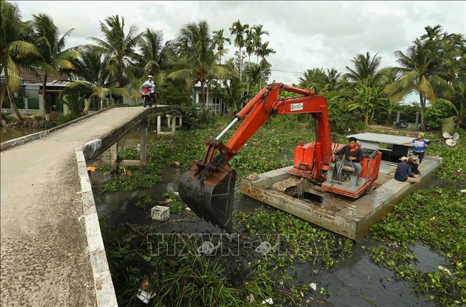 Dùng máy xúc dọn dẹp lục bình và rác thải trên tuyến kênh thủy lợi qua xã Vĩnh Thuận Đông. Ảnh: Duy Khương – TTXVN