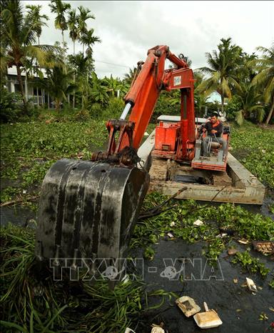 Dùng máy xúc dọn dẹp lục bình và rác thải trên tuyến kênh thủy lợi qua xã Vĩnh Thuận Đông. Ảnh: Duy Khương – TTXVN