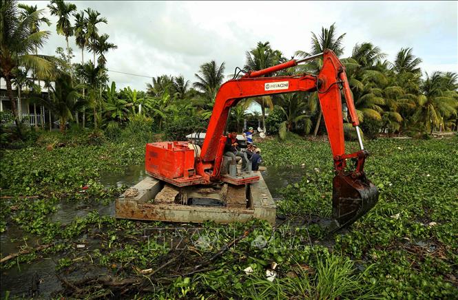 Dùng máy xúc dọn dẹp lục bình và rác thải trên tuyến kênh thủy lợi qua xã Vĩnh Thuận Đông. Ảnh: Duy Khương – TTXVN