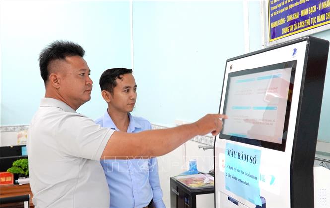 Công chức Trung tâm phục vụ hành chính công xã Bình An (An Giang) hướng dẫn người dân đăng ký hồ sơ thủ tục. Ảnh: Văn Sĩ - TTXVN 