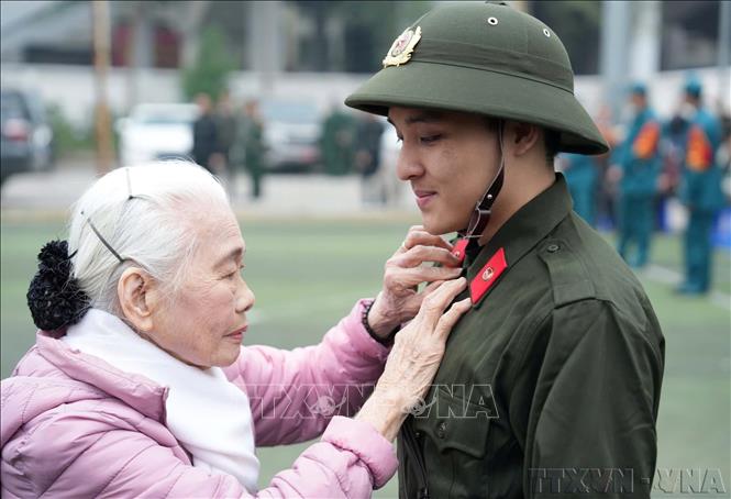 Bà Nguyễn Thị Minh Thuận (90 tuổi) tiễn cháu lên đường thực hiện nghĩa vụ công an nhân dân tại điểm giao, nhận quân Quận Đống Đa, Hà Nội (2/2025). Ảnh: Phạm Kiên - TTXVN