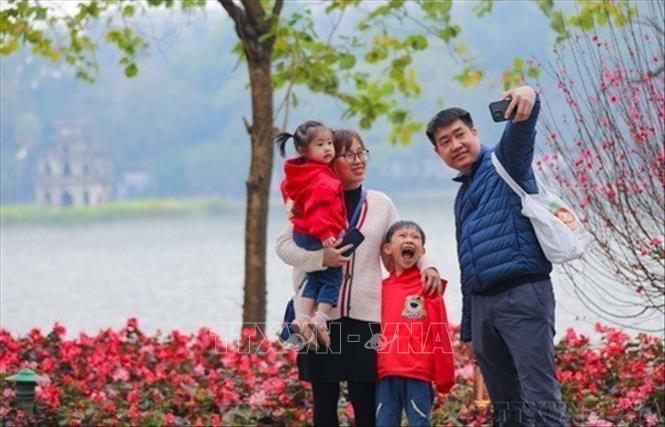 Cả gia đình cùng nhau ghi lại khoảnh khắc của mùa Xuân bên hồ Gươm (1/2023). Ảnh: Thanh Tùng - TTXVN