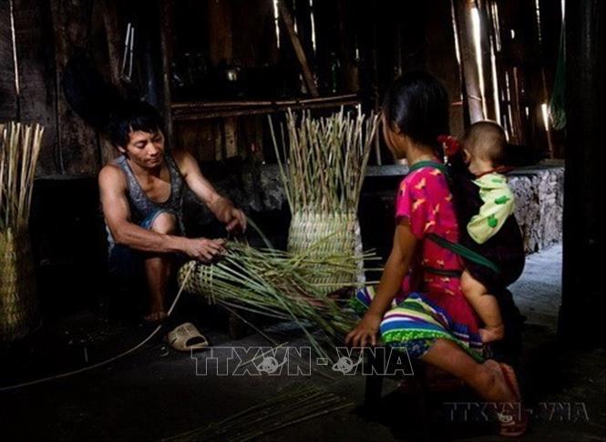 Trẻ em chăm chú xem đan quẩy tấu, một vật dụng gắn liền với cuộc sống thường ngày, được xem là vật “bất ly thân” của người dân tộc Mông. Ảnh: Nam Thái - TTXVN