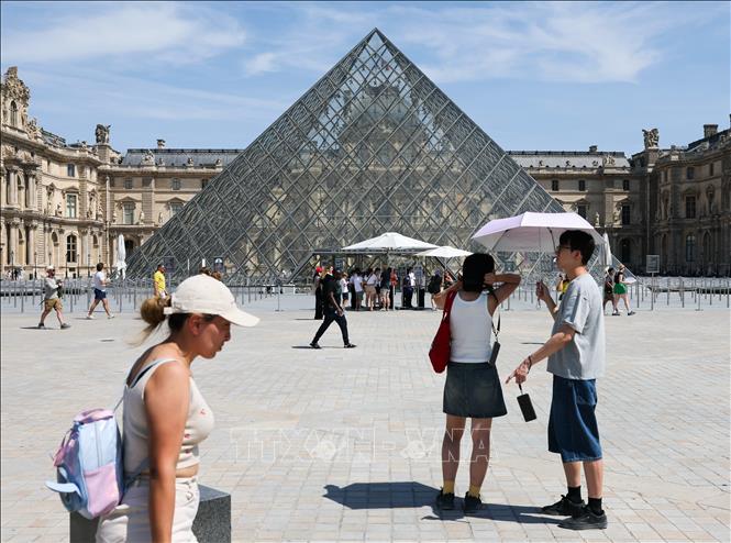 Du khách che ô chống nắng khi tham quan viện bảo tàng Louvre ở Paris, Pháp ngày 25/6/2026. Ảnh: THX/TTXVN