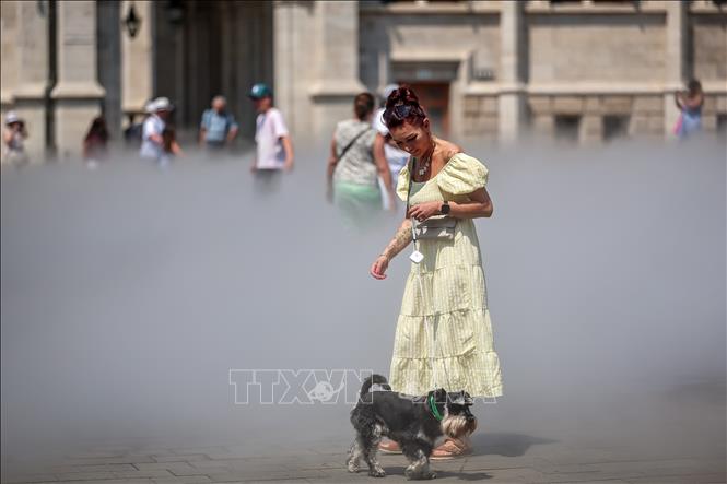 Người dân làm mát bằng hệ thống phun sương ở Budapest, Hungary ngày 24/6/2026. Ảnh: THX/TTXVN