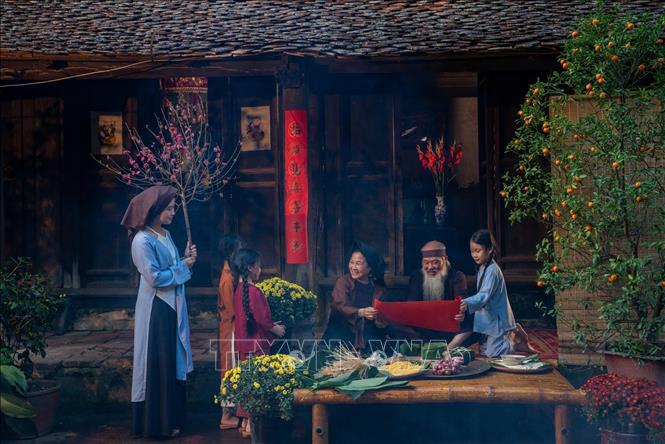 Khoảnh khắc con cháu quây quần bên ông bà dưới hiên nhà cũ, gợi nhắc về cội nguồn, lan tỏa giá trị thiêng liêng của tình thân, gìn giữ nếp nhà và truyền thống gia đình Việt Nam. Ảnh: Khánh Hòa - TTXVN