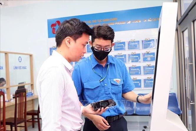 Đoàn viên Đoàn Thanh niên phường Tam Thắng hướng dẫn người dân thực hiện dịch vụ công trực tuyến tại Trung tâm Phục vụ hành chính công phường. Ảnh: TTXVN phát