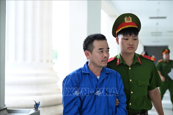 Lực lượng cảnh sát hỗ trợ tư pháp dẫn giải bị cáo Đinh Văn Long tới Tòa án.
Ảnh: Kim Anh - TTXVN