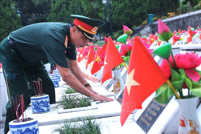 Cựu chiến binh lặng lẽ đặt tay lên bia mộ đồng đội tại Nghĩa trang Liệt sĩ Quốc gia Vị Xuyên, tỉnh Tuyên Quang. Ảnh: Minh Tâm-TTXVN