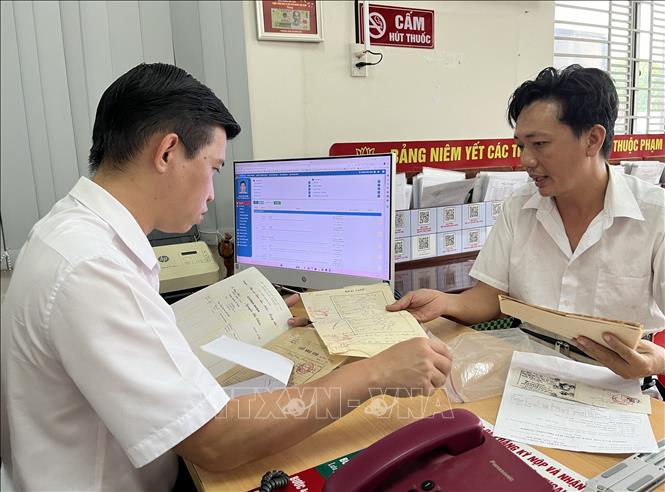 Người dân trực tiếp hỏi chuyên viên Trung tâm Phục vụ hành chính công phường Long An về hồ sơ đất đai khó giải quyết. Ảnh: Đức Hạnh - TTXVN 