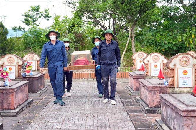 Cán bộ đội quy tập đưa hài cốt liệt sĩ đến khu vực lấy mẫu sinh phẩm. Ảnh: Hữu Quyết – TTXVN