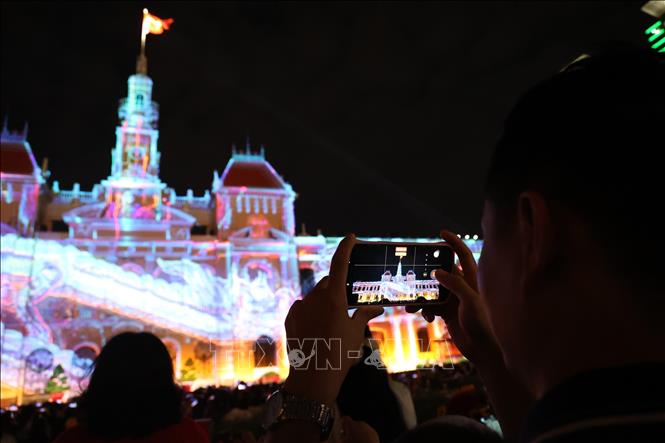 Người dân lưu lại hình ảnh ấn tượng từ những màn trình chiếu 3D mapping. Ảnh: Hồng Đạt - TTXVN