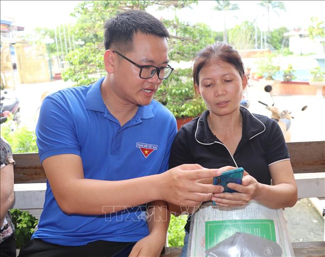 Đoàn viên thanh niên trực tiếp hỗ trợ người dân xã Giao Bình, tỉnh Ninh Bình nâng cao kỹ năng số. Ảnh: Thùy Dung - TTXVN