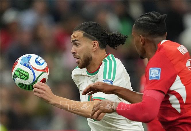 Pha tranh bóng giữa cầu thủ Ramiz Zerrouki (trái) của Algeria và Manuel Akanji của Thụy Sĩ. Ảnh: THX/TTXVN phát
