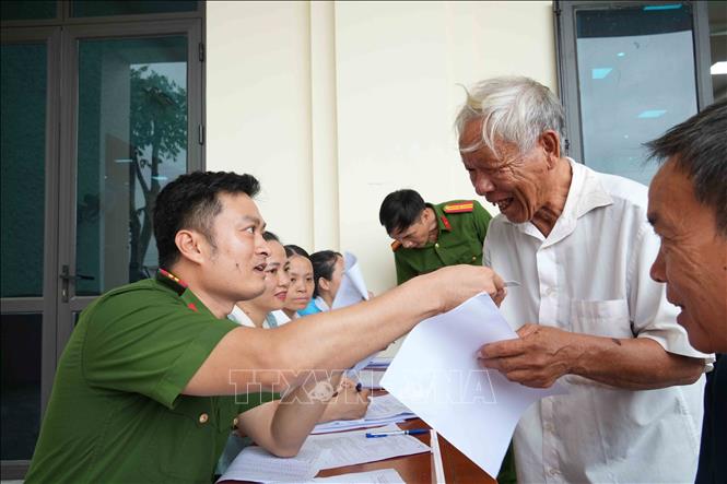 Lực lượng chức năng hướng dẫn người dân hoàn thiện hồ sơ, bảo đảm việc thu nhận mẫu ADN diễn ra thuận lợi. Ảnh: Hữu Quyết - TTXVN