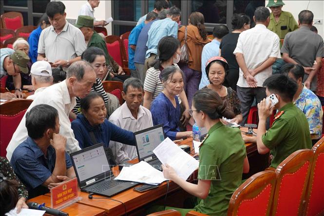 Cán bộ Công an hướng dẫn thân nhân liệt sĩ đối chiếu thông tin, hoàn thiện hồ sơ trước khi lấy mẫu ADN. Ảnh: Hữu Quyết - TTXVN