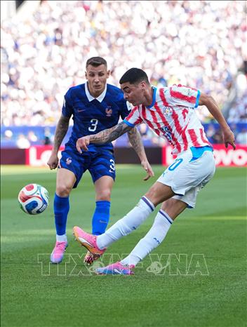 Miguel Almiron (phải) của Paraguay dứt điểm trước sự kèm cặp của cầu thủ Pháp. Ảnh: THX/TTXVN phát