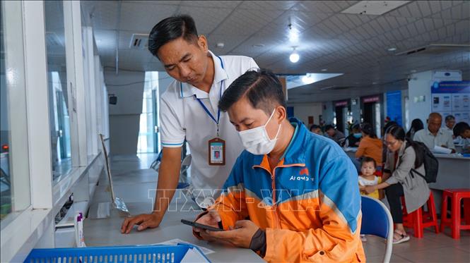 Thành viên Tổ Công nghệ số cộng đồng hướng dẫn người dân cài đặt và sử dụng các ứng dụng số, góp phần lan tỏa Phong trào “Bình dân học vụ số” đến từng hộ gia đình. Ảnh: Minh Phú – TTXVN