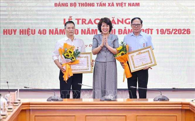 Đồng chí Nguyễn Thị Hoàng Vân, Phó Bí thư Đảng ủy, Trưởng Ban Tuyên giáo và Dân vận Đảng ủy các cơ quan Đảng Trung ương trao tặng Huy hiệu 30 năm, 40 năm tuổi Đảng cho đồng chí Phạm Huy Minh, Đảng bộ Ban Biên tập Ảnh và đồng chí Nguyễn Văn Bằng, Chi bộ Trung tâm Hợp tác quốc tế thông tấn. Ảnh: Minh Đức – TTXVN