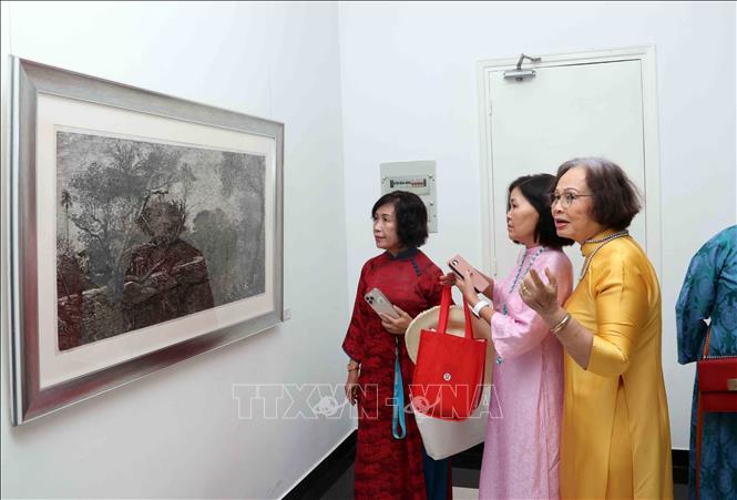 Khách tham quan chiêm ngưỡng tác phẩm tranh khắc gỗ của họa sĩ Lê Phi Hùng. Ảnh: Xuân Khu- TTXVN