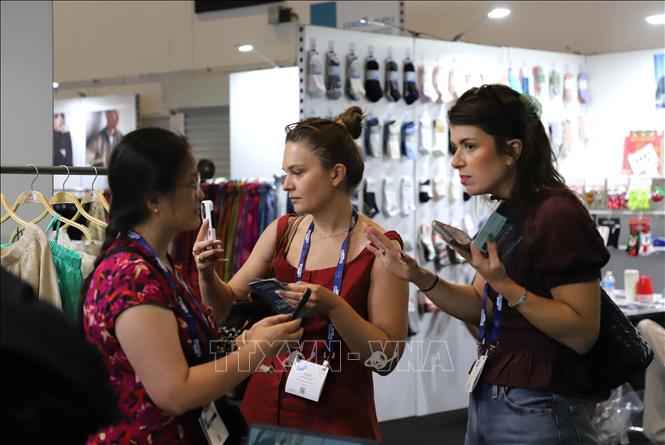 Hai người mua tìm hiểu thông tin sản phẩm tại một gian hàng dệt may Việt Nam tại Source Fashion 2026. Ảnh: Hữu Tiến - PV TTXVN tại Anh