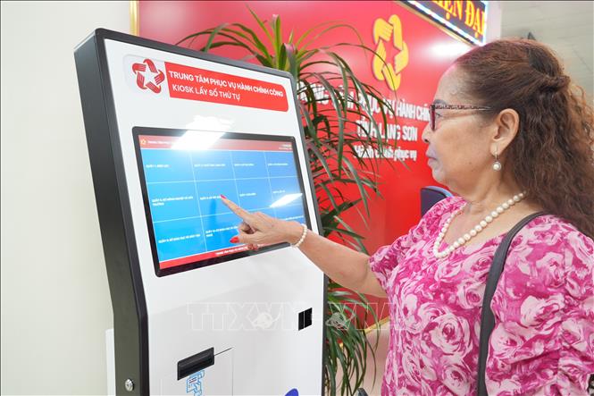 Người dân đến làm thủ tục hành chính lấy số thứ tự tại trung tâm. Ảnh: Tiến Vĩnh – TTXVN 