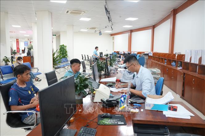 Cán bộ bộ phận một cửa tiếp nhận và giải quyết thủ tục hành chính cho người dân và doanh nghiệp đến làm thủ tục. Ảnh: Tiến Vĩnh – TTXVN