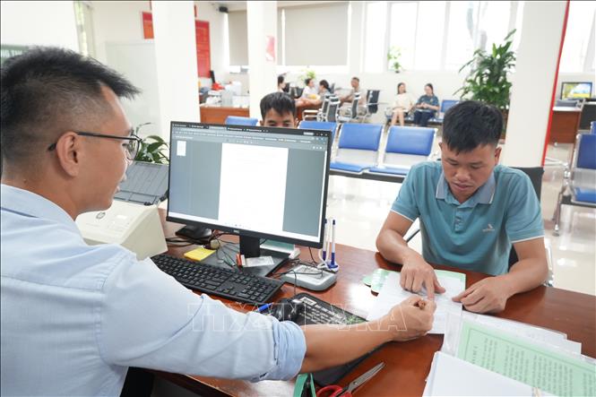 Cán bộ bộ phận một cửa hướng dẫn hoàn thiện thủ tục cho người dân. Ảnh: Tiến Vĩnh – TTXVN 